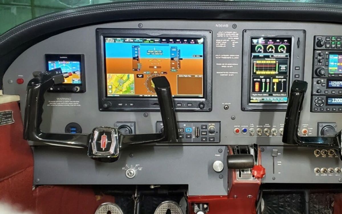 The instrument panel of the Cherokee 180: two large Garmin glass displays side by side, a radio stack to the right, and twin control yokes over a red interior.